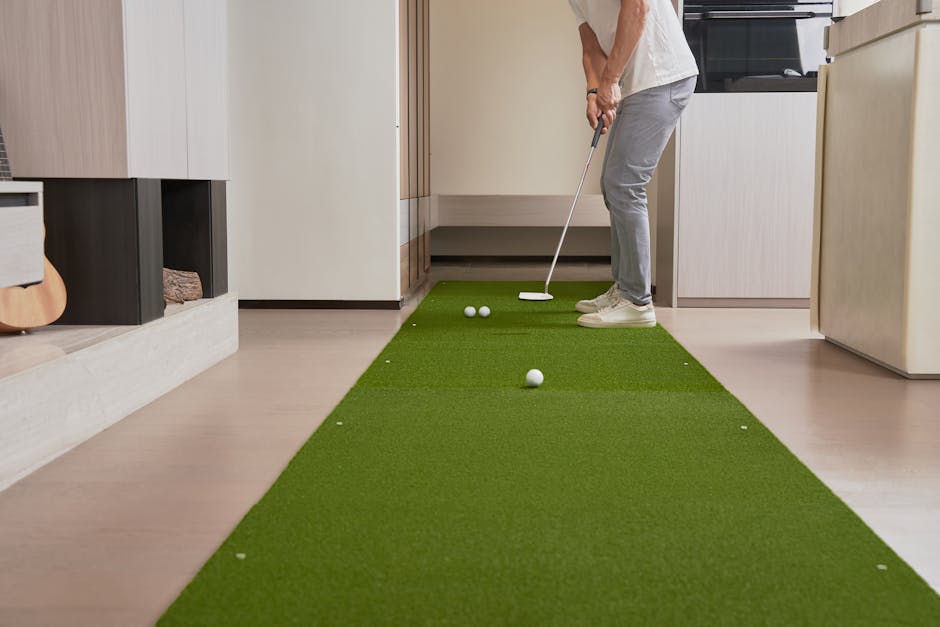 Hombre practicando putts de golf sobre una alfombra de césped artificial en interiores.