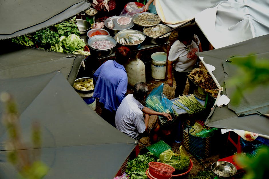 Un animado mercado callejero al aire libre con productos frescos y mariscos, visto desde arriba.