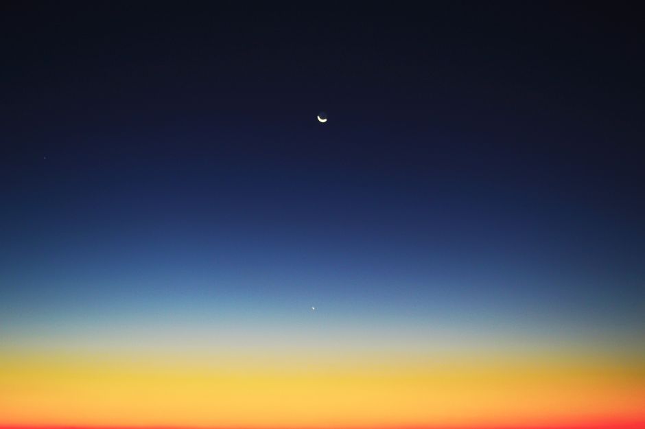 Luna creciente y planeta visibles en un cielo crepuscular colorido sobre Mahajanga, Madagascar.