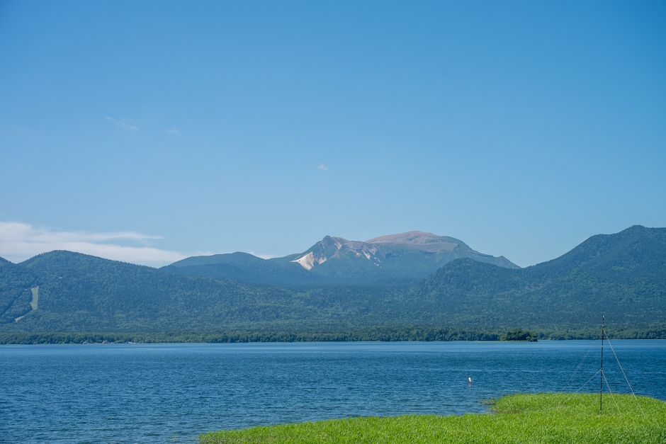 Hermoso día claro en el lago Akan, Hokkaido, Japón, con las tranquilas aguas azules y el telón de fondo montañoso.