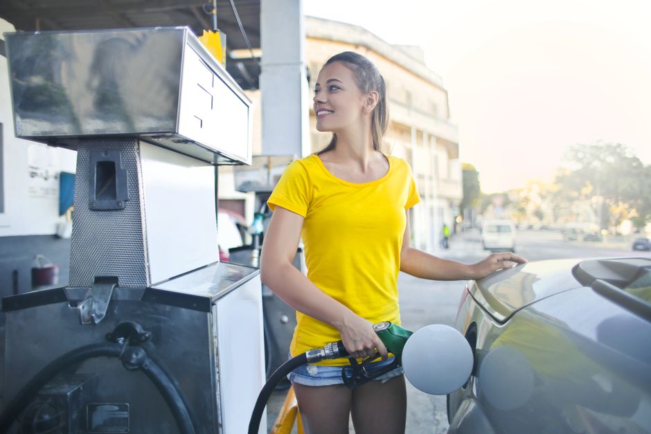 Mujer En Camisa Amarilla Mientras Llena Su Coche Con Gasolina