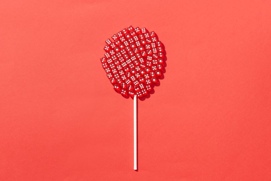 Concepto artístico de un chupachups hecho de dados rojos contra un fondo rojo vibrante, enfatizando la creatividad y el contraste de colores.