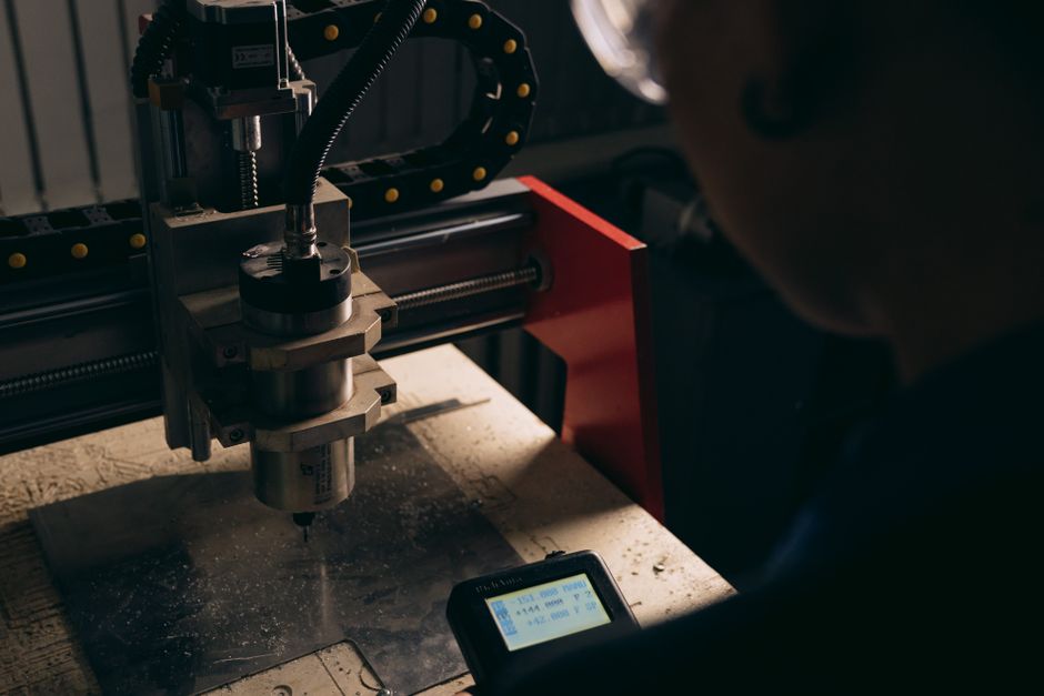 Una vista detallada de una máquina CNC siendo operada por una persona en el interior con iluminación tenue.