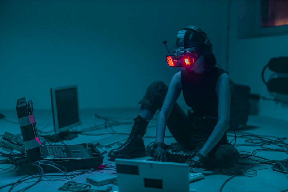 Una persona en un visor de VR hackeando en un entorno de luces de neón y ambiente sombrío.