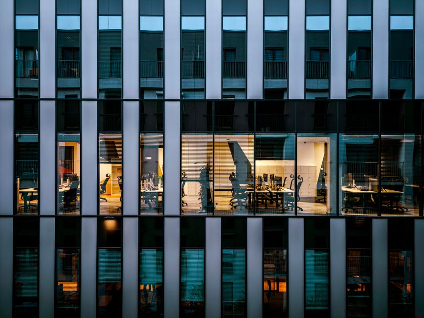 Oficina iluminada dentro de un moderno edificio de vidrio, mostrando la arquitectura y el diseño del espacio de trabajo.