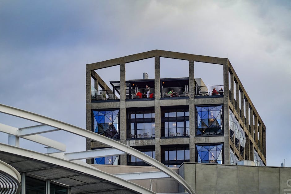 Edificio contemporáneo con terraza en la azotea y fachada geométrica de cristal.