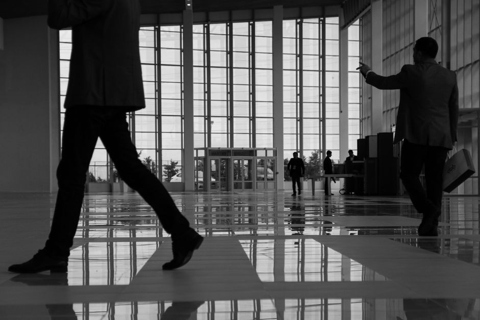 Profesionales de negocios caminan a través de un espacio interior moderno con paneles de vidrio.