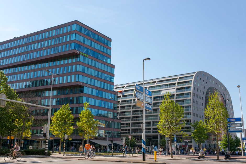 Vista de la calle de la arquitectura moderna y la actividad bulliciosa en Rotterdam bajo un cielo despejado.