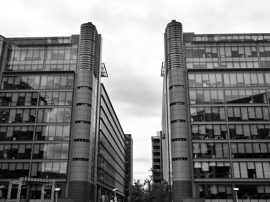 Foto en blanco y negro de edificios modernos de vidrio con reflejos en un entorno urbano.