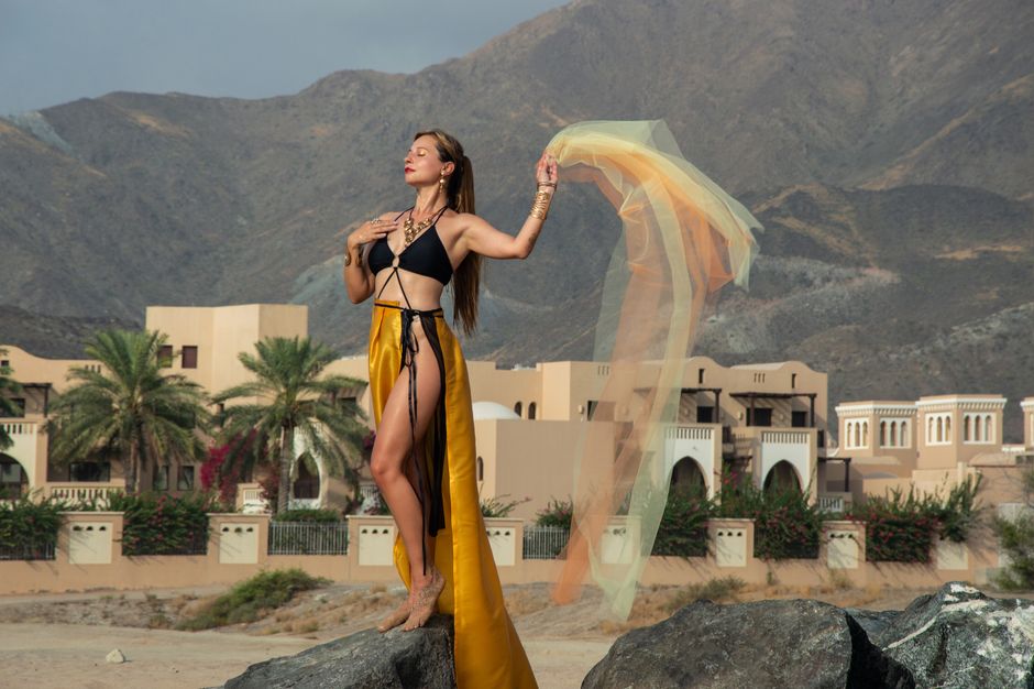 Mujer a la moda posando elegantemente con un fondo de montañas y desierto en un resort.