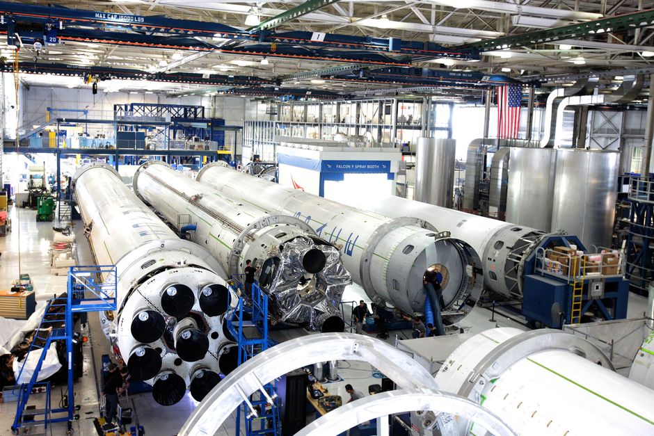 Vista de una línea de ensamblaje de naves espaciales con cohetes en un amplio hangar.