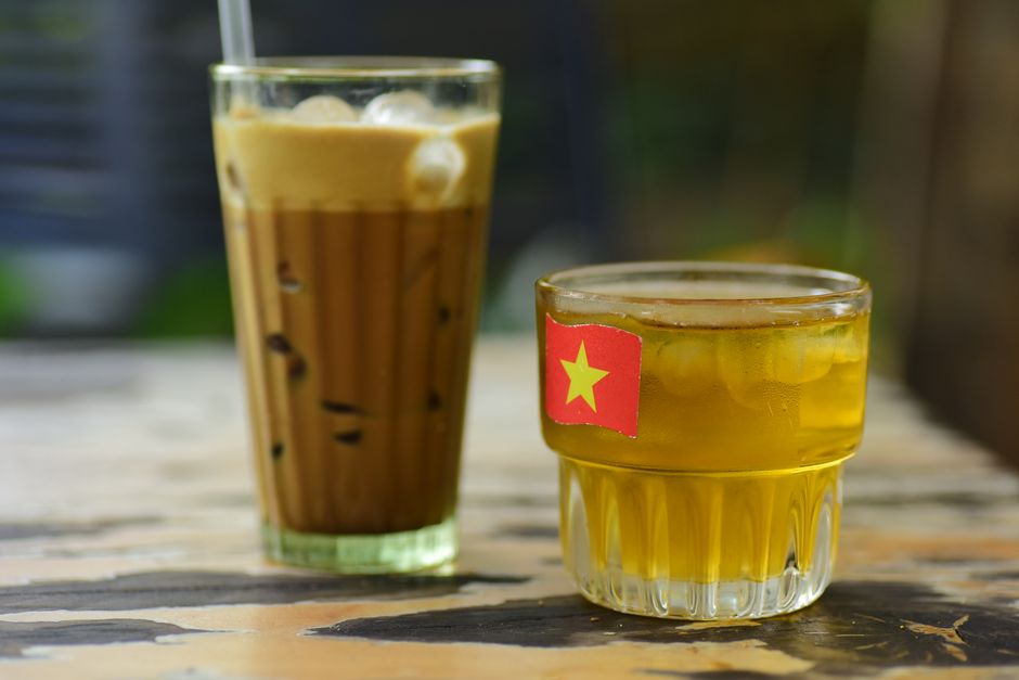 Vasos de café y té vietnamita helados en una mesa rústica al aire libre.