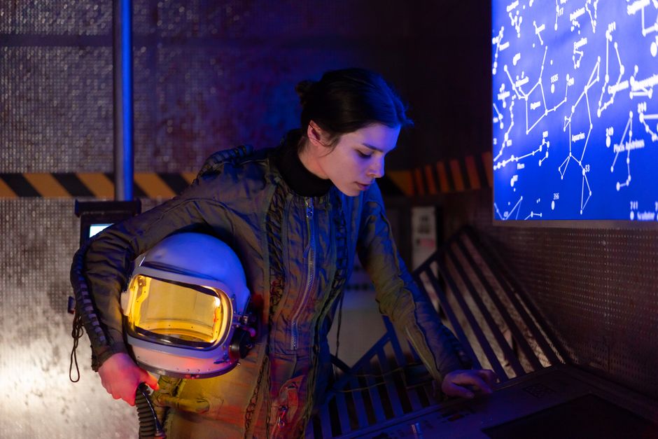 Mujer astronauta en un ambiente futurista examinando un mapa estelar digital.