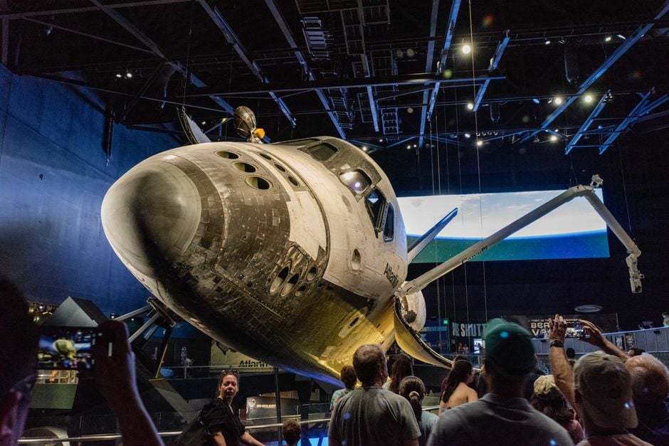 Multitud admira el Space Shuttle Atlantis en una exposición de museo espacial interior.