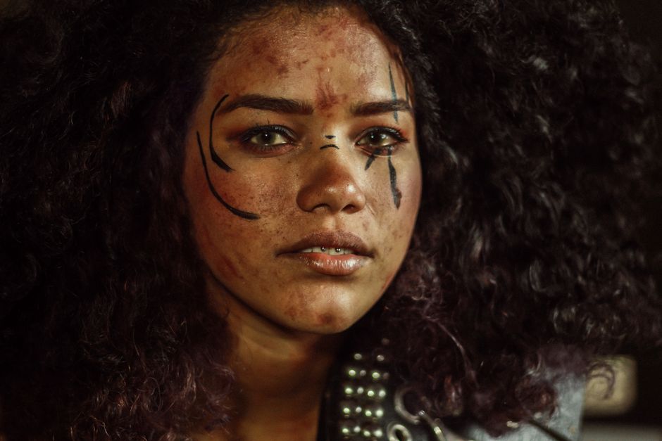 Retrato en primer plano de una mujer con maquillaje expresivo y cabello rizado bajo iluminación artística.