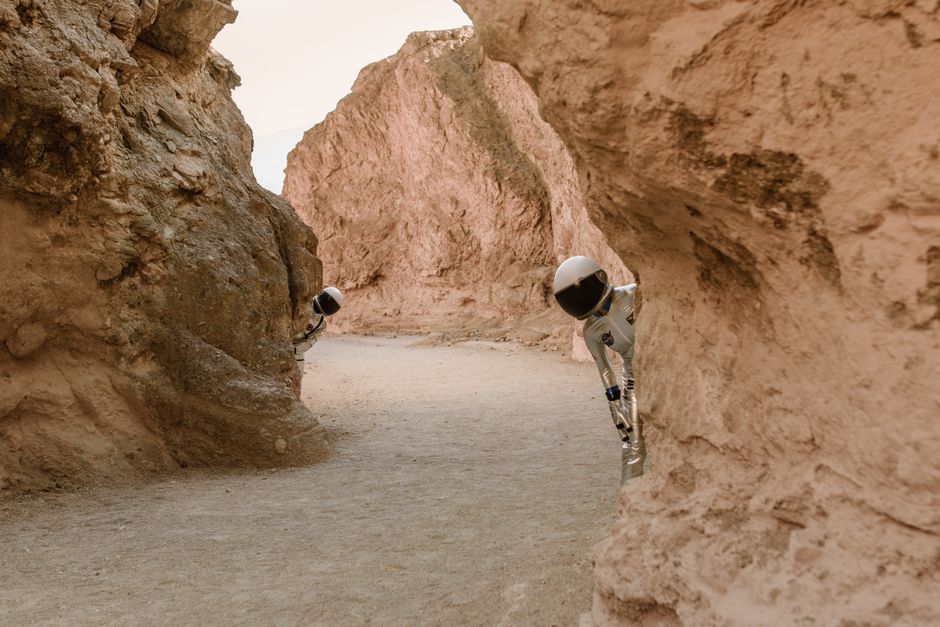 Los astronautas asoman detrás de rocas en un paisaje extraterrestre de fantasía.