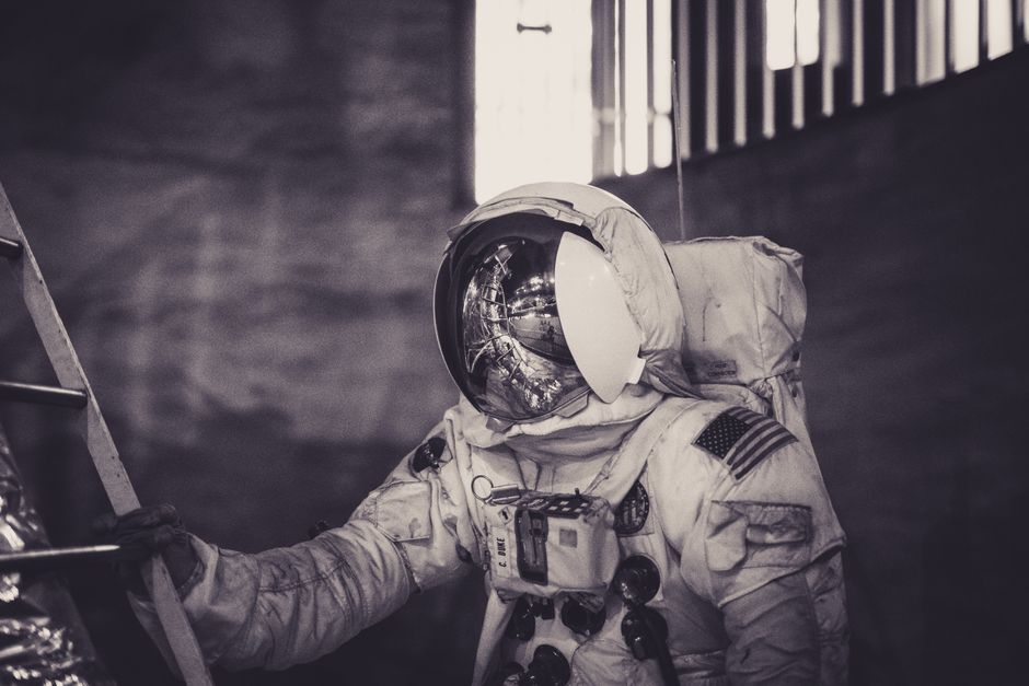 Astronauta con traje espacial subiendo una escalera en un entorno oscuro.