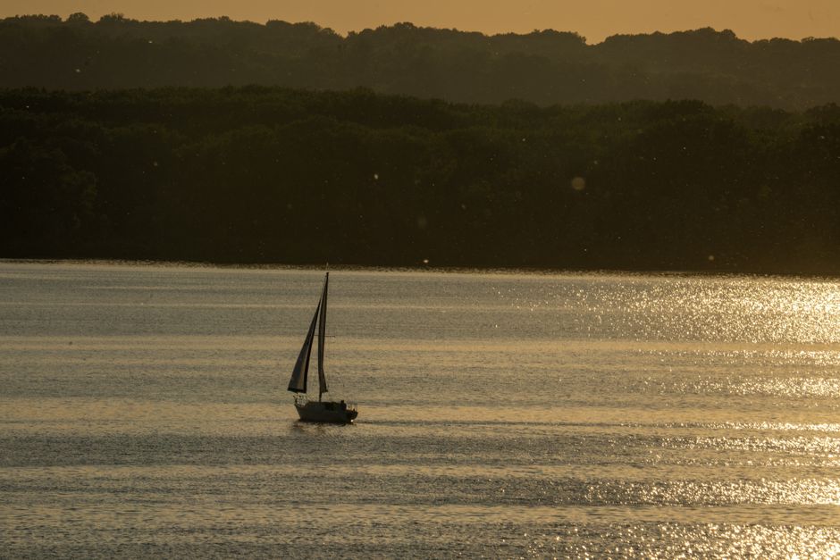 Un velero pacífico deslizándose por las aguas brillantes del Lago Pepin al atardecer.