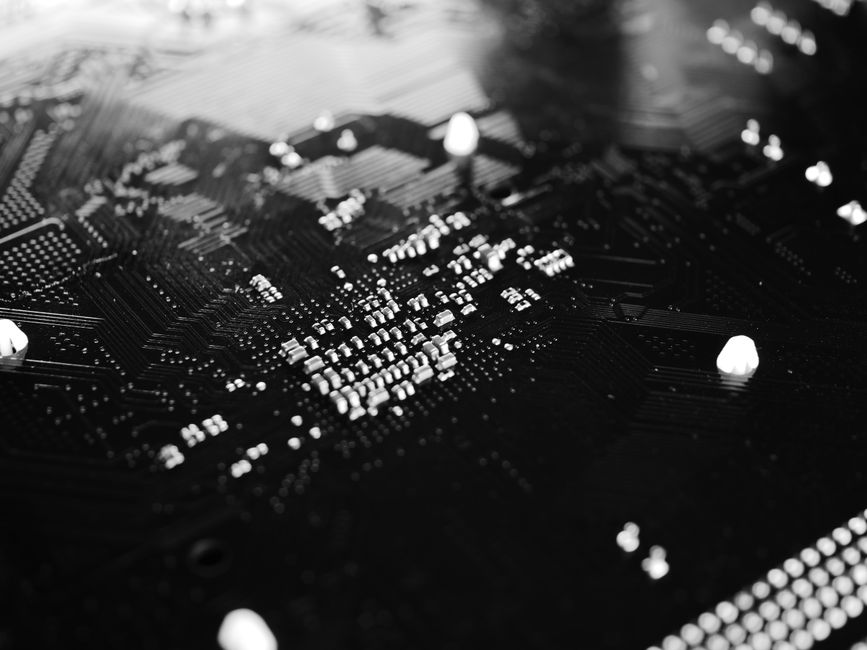 Primer plano en blanco y negro de una placa de circuito con patrones y componentes intrincados.