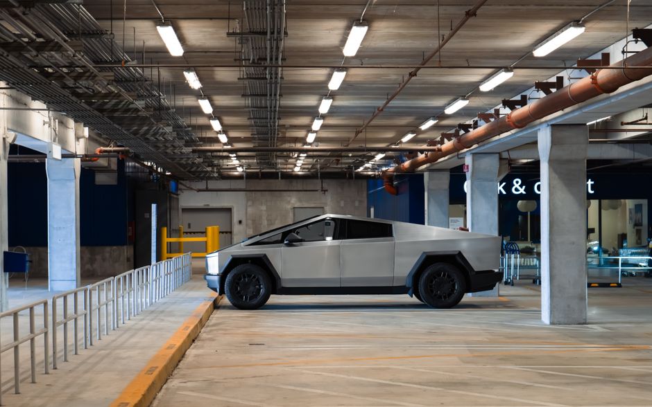 Un Cybertruck eléctrico está aparcado en un garaje subterráneo moderno, mostrando un diseño automotriz futurista.