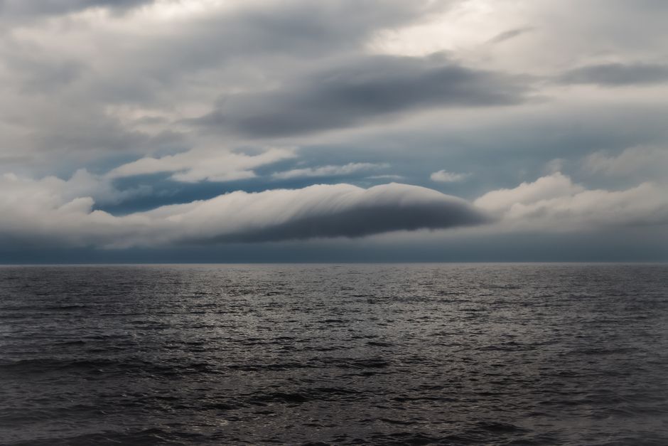 Una escena oceánica melancólica con un cielo tormentoso dramático y aguas oscuras y agitada.