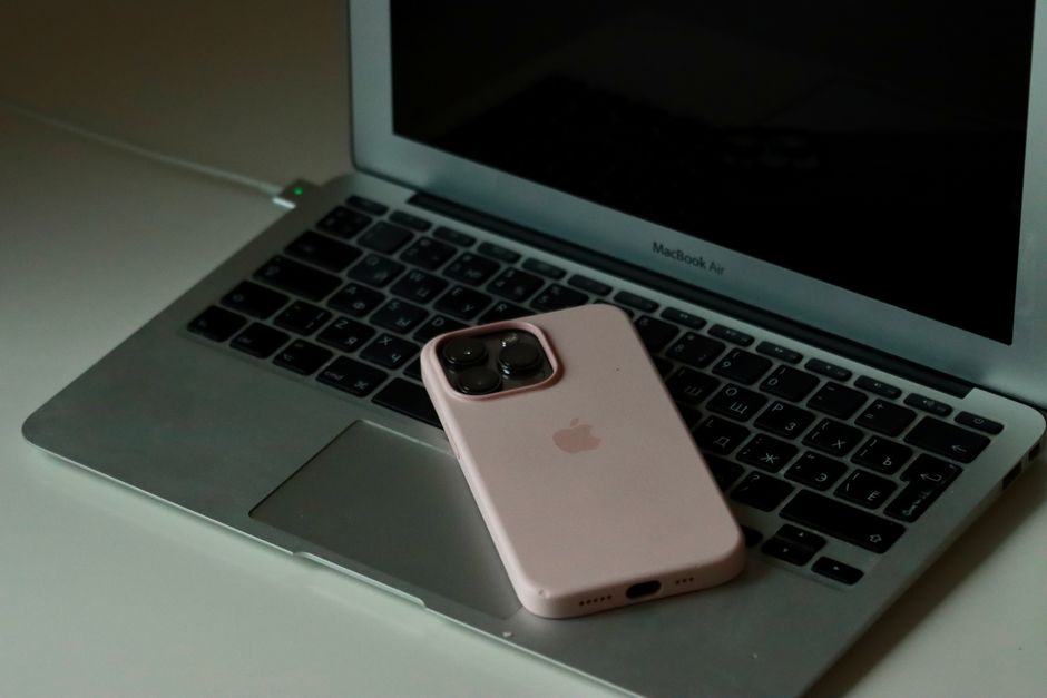 Un smartphone reposa sobre el teclado de un MacBook Air, mostrando la sinergia de la tecnología moderna.
