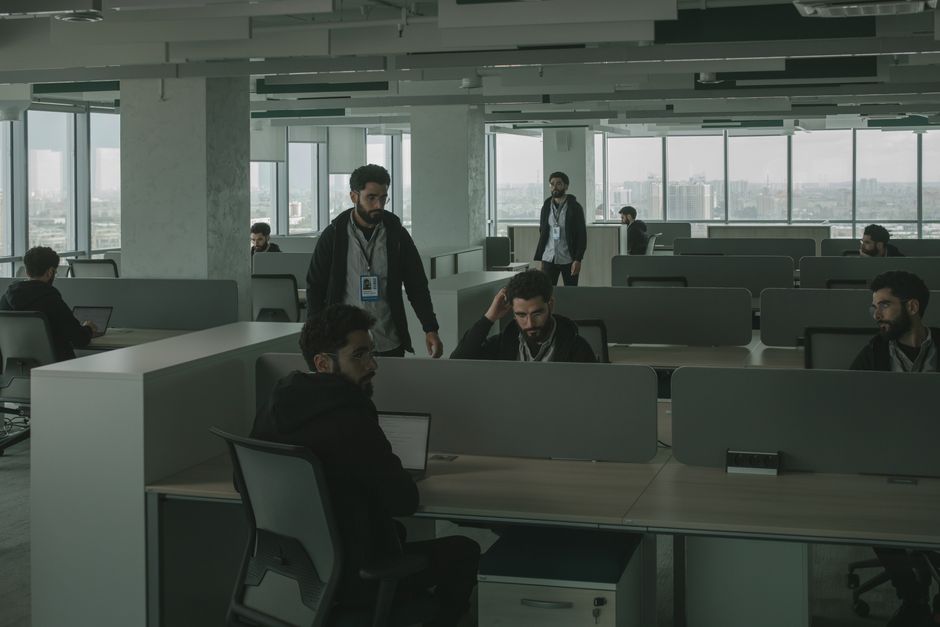Una escena surrealista de un hombre clonado múltiples veces en un entorno de oficina, simbolizando el trabajo en equipo y la multitarea.
