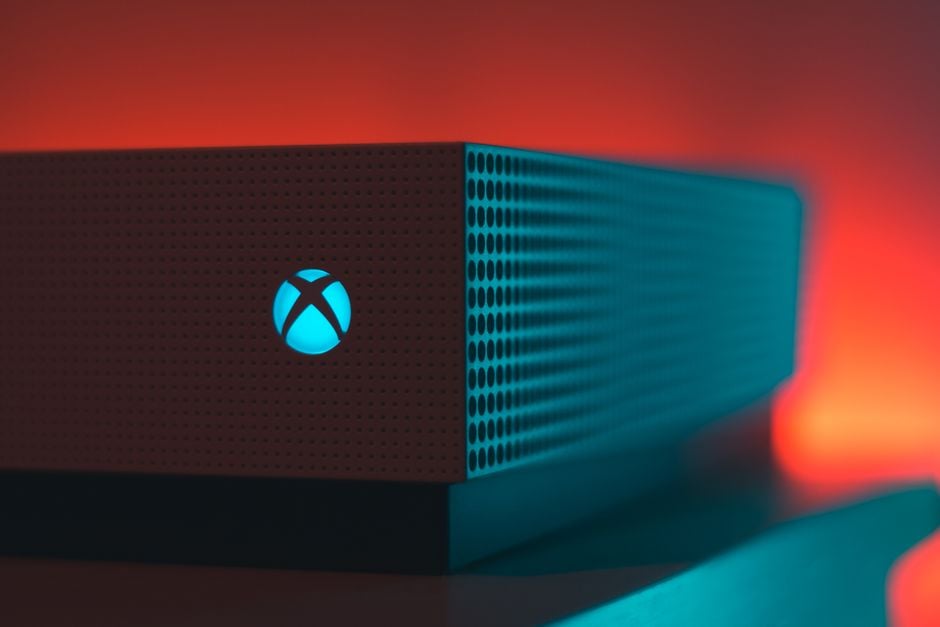 Primer plano de una consola de juegos iluminada con un aura de luz roja y azul.