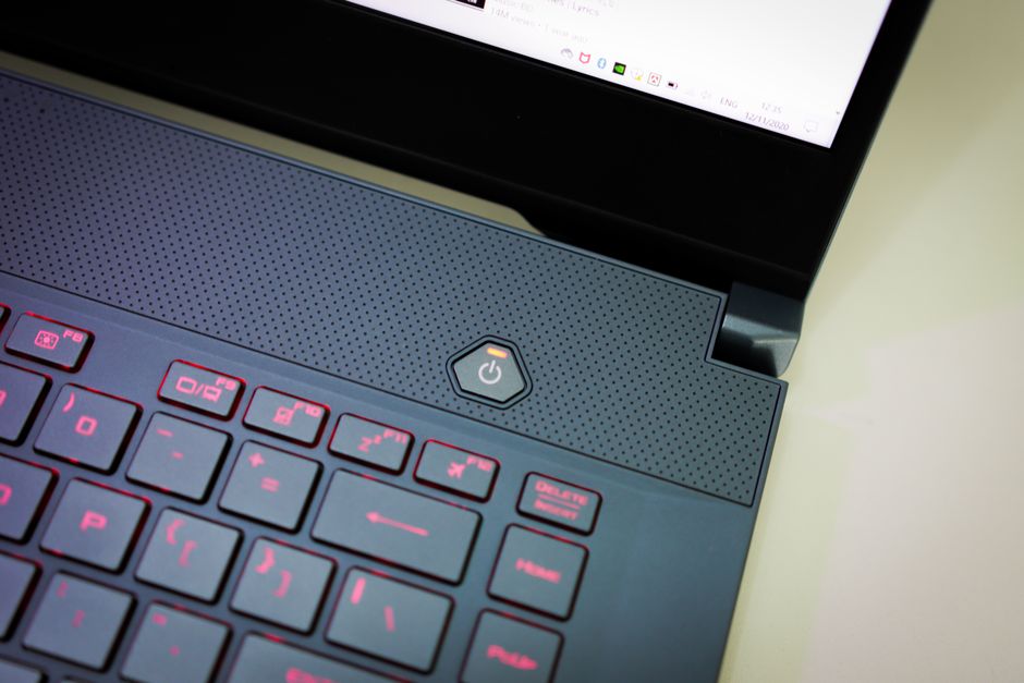 Imagen de primer plano detallada centrada en el botón de encendido y el teclado iluminado de un laptop moderno.