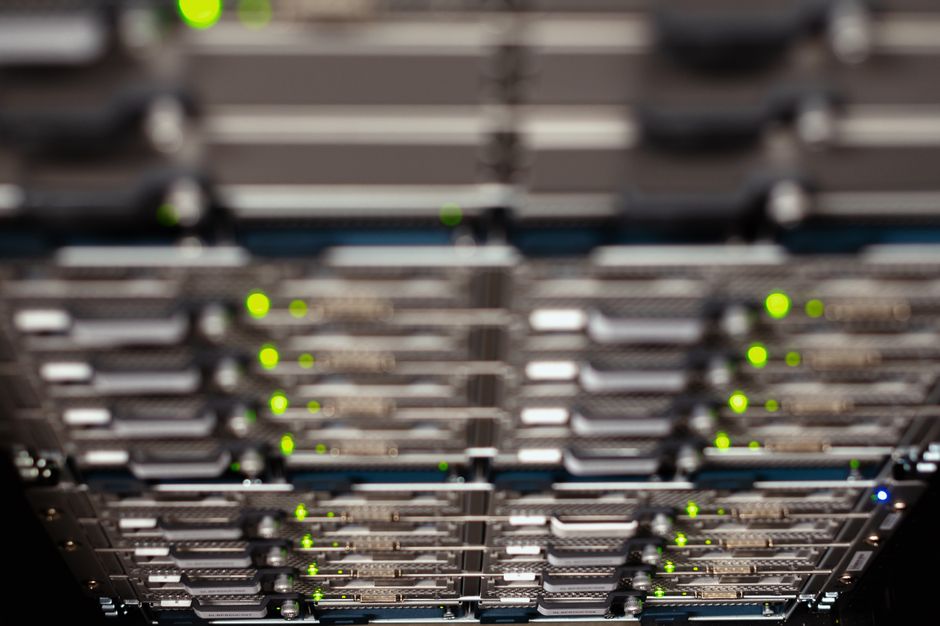 Acercamiento a un rack de servidores de red con LEDs parpadeantes, mostrando conexiones Ethernet y paneles de parcheo.