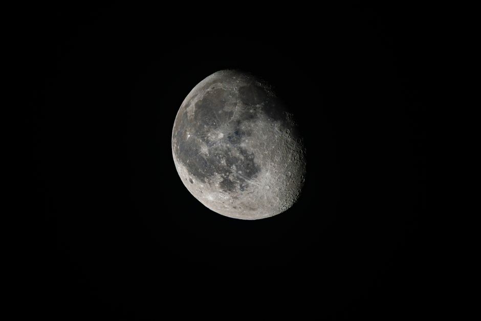 Imagen detallada de la luna gibosa menguante contra un cielo oscuro, que resalta sus cráteres y la textura de su superficie.