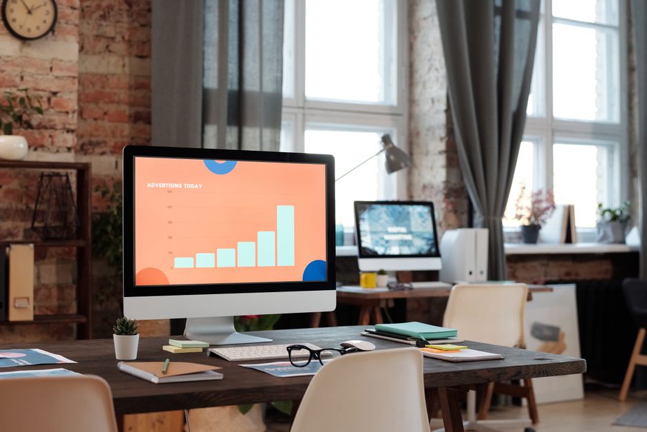 Una configuración de oficina elegante con un ordenador mostrando un gráfico sobre tendencias publicitarias.