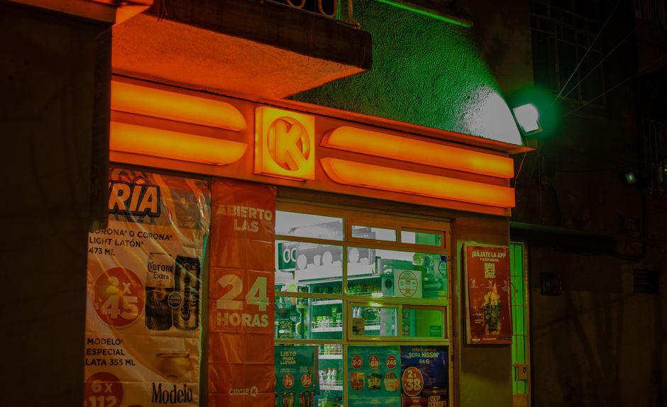 Una tienda de conveniencia bien iluminada con luces de neón por la noche, que muestra colores vibrantes y señalización.