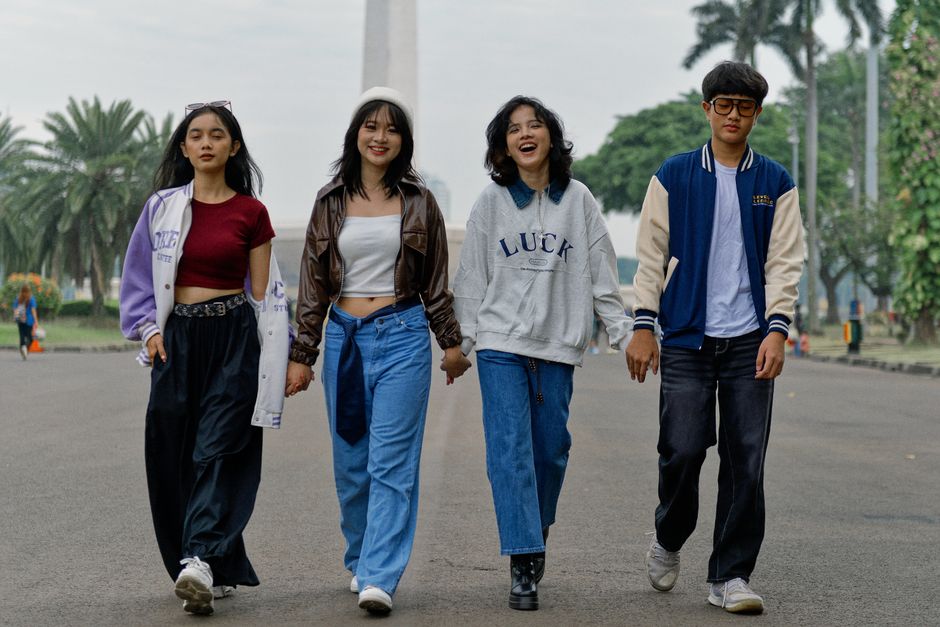 Cuatro jóvenes adultos paseando al aire libre, luciendo un estilo urbano informal.