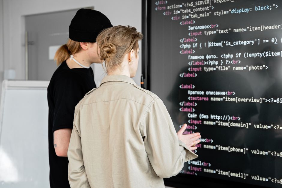 Dos desarrolladores examinando código en una pantalla grande en un espacio de oficina moderno, centrados en el desarrollo web.