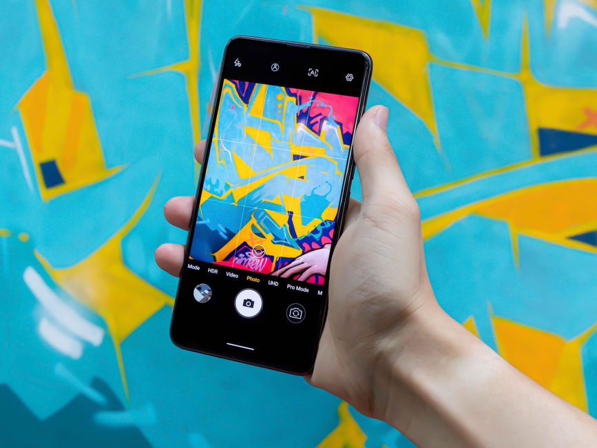 Un smartphone captura arte graffiti abstracto vibrante, mostrando creatividad y tecnología.