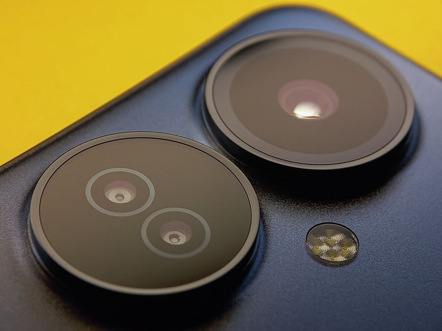 Primer plano extremo de las lentes de cámara de smartphone con un fondo amarillo vibrante, mostrando tecnología moderna.