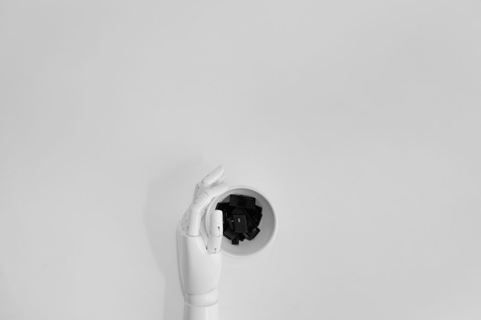 Una mano robótica agarrando teclas de teclado negras en un entorno minimalista.