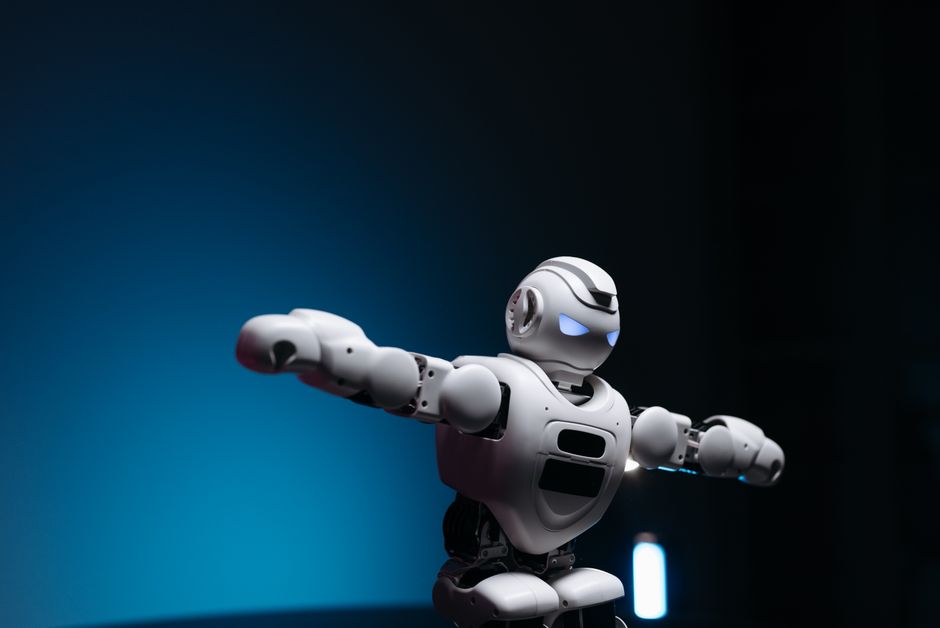 Primer plano de un juguete robot futurista con ojos brillantes sobre un fondo azul, simbolizando innovación.