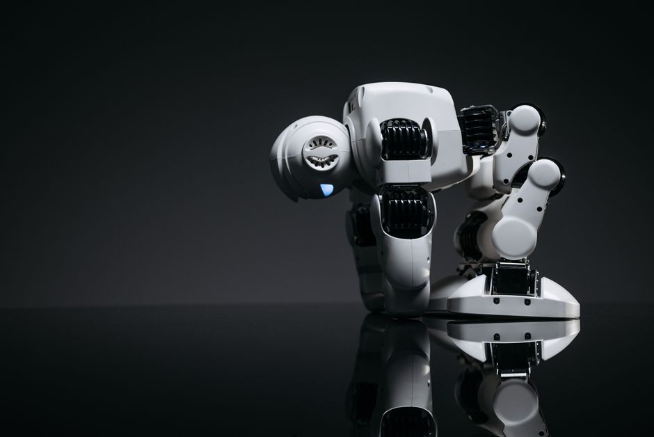 Un juguete robot moderno representado en un entorno de estudio con su reflejo visible en una superficie oscura.