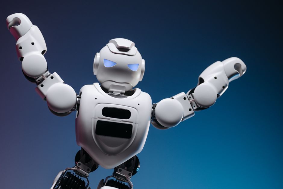 Un robot futurista en un estudio, adoptando una pose poderosa con los brazos levantados.