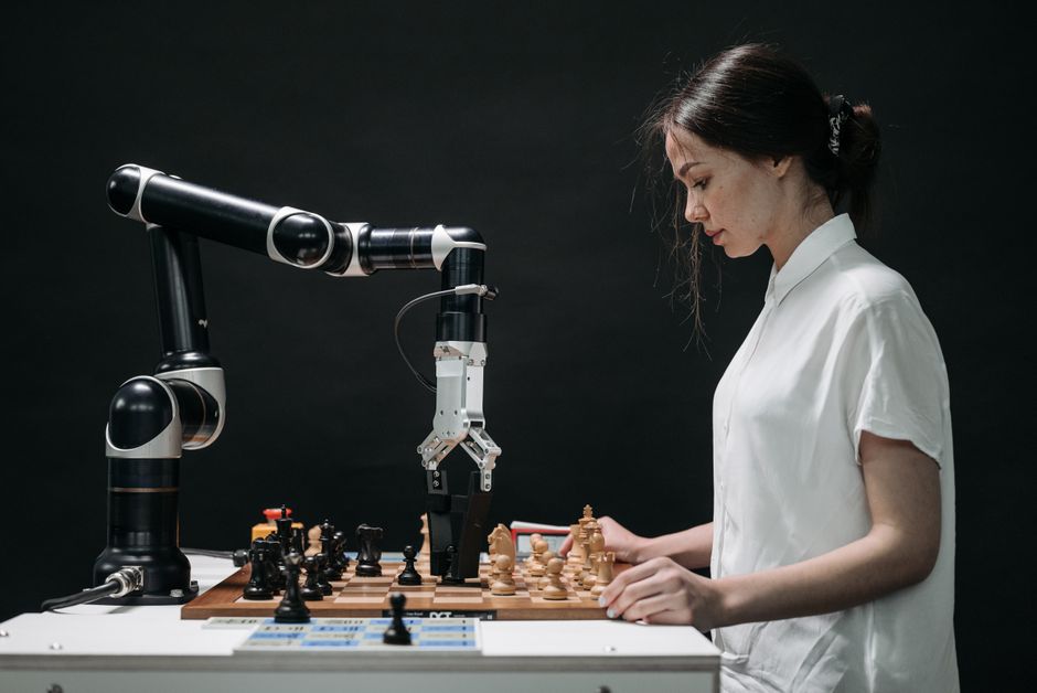 Un robot y una mujer participan en una partida de ajedrez, mostrando tecnología y pensamiento estratégico.