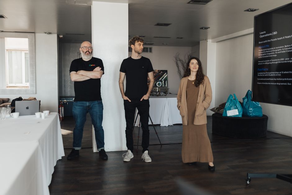 Tres profesionales presentando en una oficina moderna con una gran pantalla.