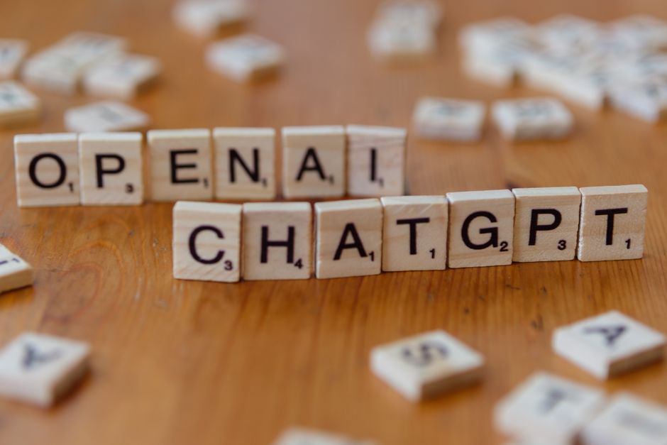 Letras de madera que deletrean 'OPENAI CHATGPT' sobre una superficie de madera, imagen enfocada.