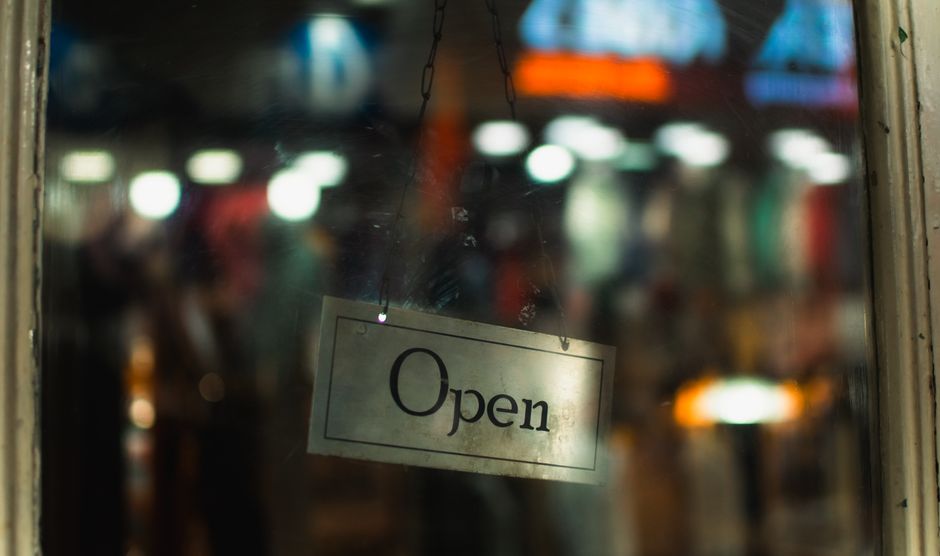 Una acogedora entrada de una tienda que muestra un cartel de abierto al anochecer en Darjeeling, India.