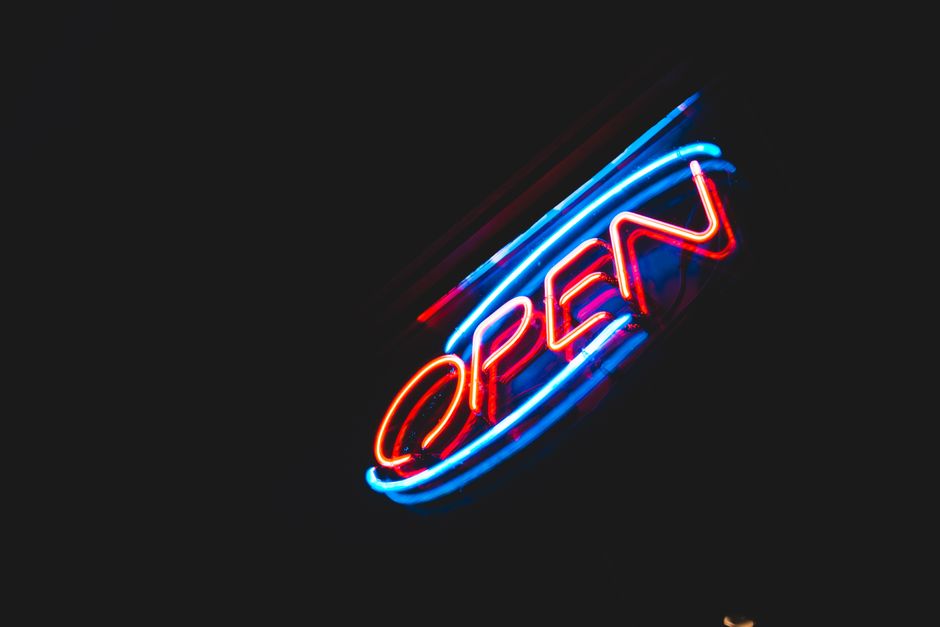 Brillante y colorido cartel de neón 'Abierto' resplandeciendo vívidamente contra un fondo oscuro.