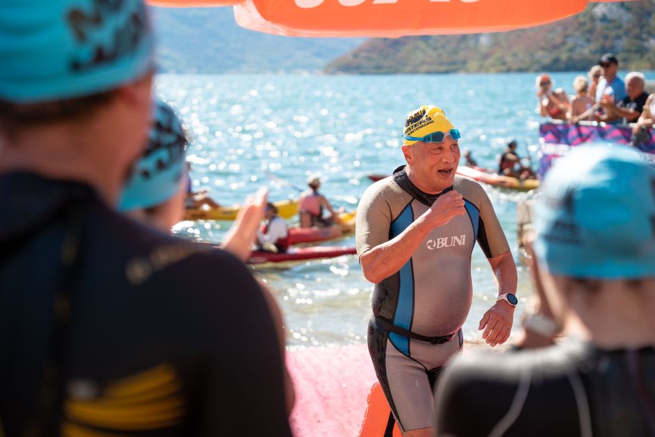 Un atleta veterano completa la prueba de natación en un triatlón celebrado en un evento soleado a orillas de un lago.
