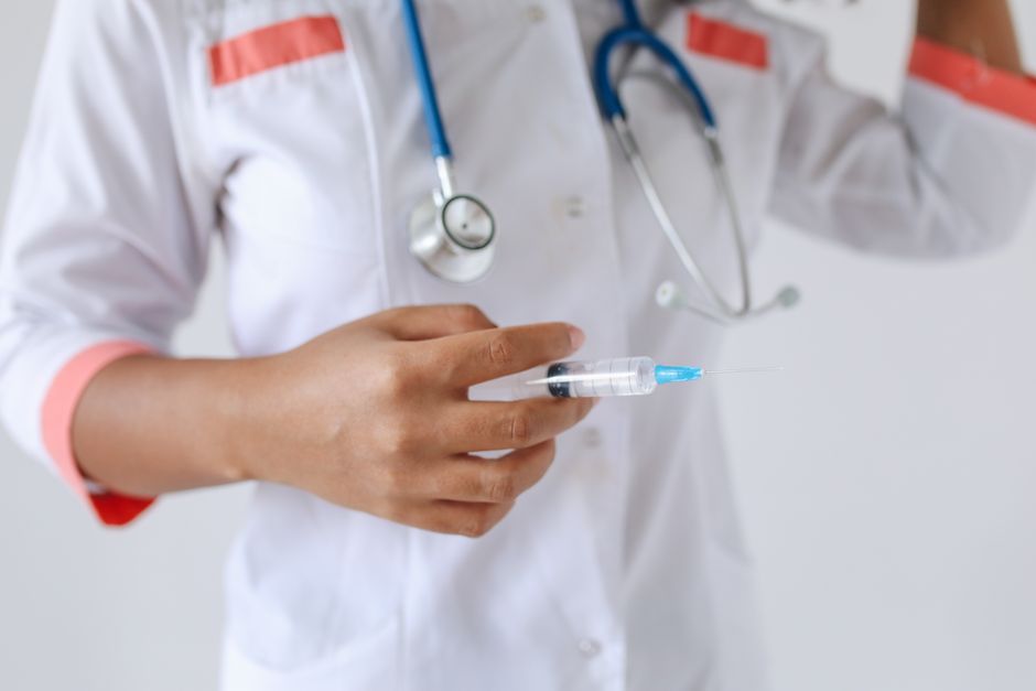 Médico con bata blanca sosteniendo una jeringa, listo para la inyección. Escena de profesional de la salud.