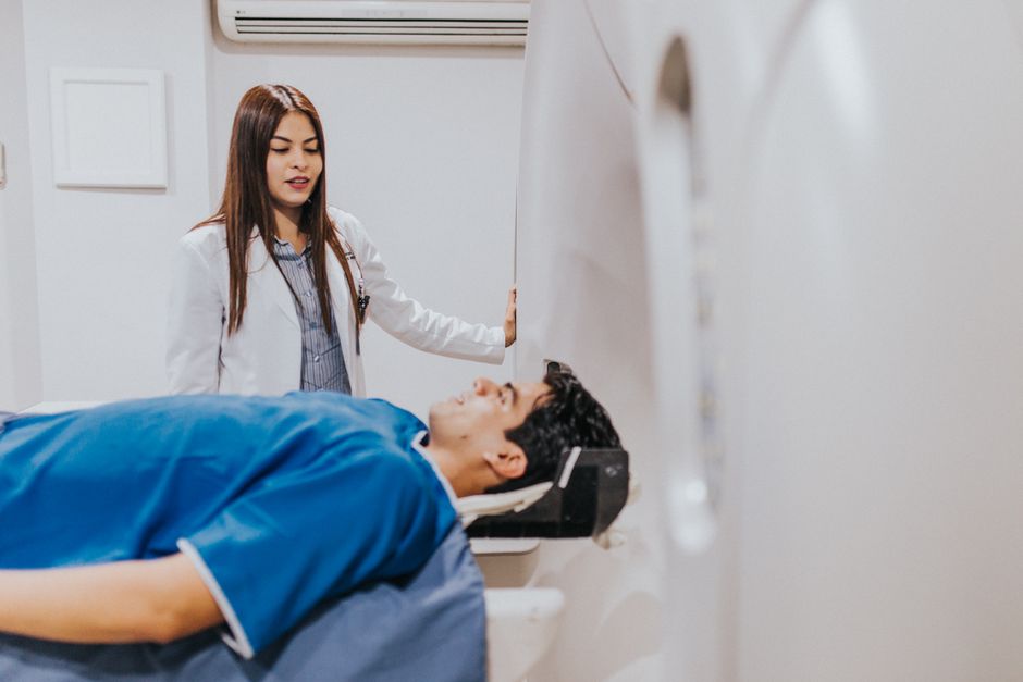 Un médico se encuentra al lado de un paciente en una sala de resonancia magnética, asegurando un proceso de examen fluido.