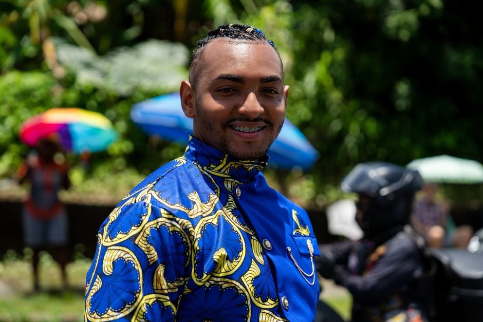 Hombre sonriente con atuendo colorido en un animado desfile en Limón, Costa Rica.